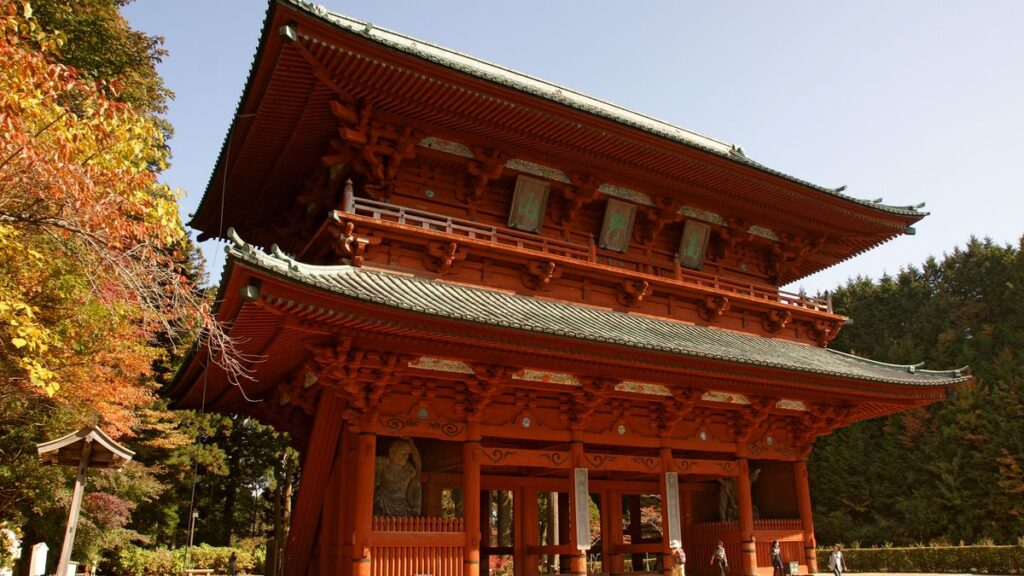 The vermilion Daimon Gate of Koyasan with autumn leaves beside it