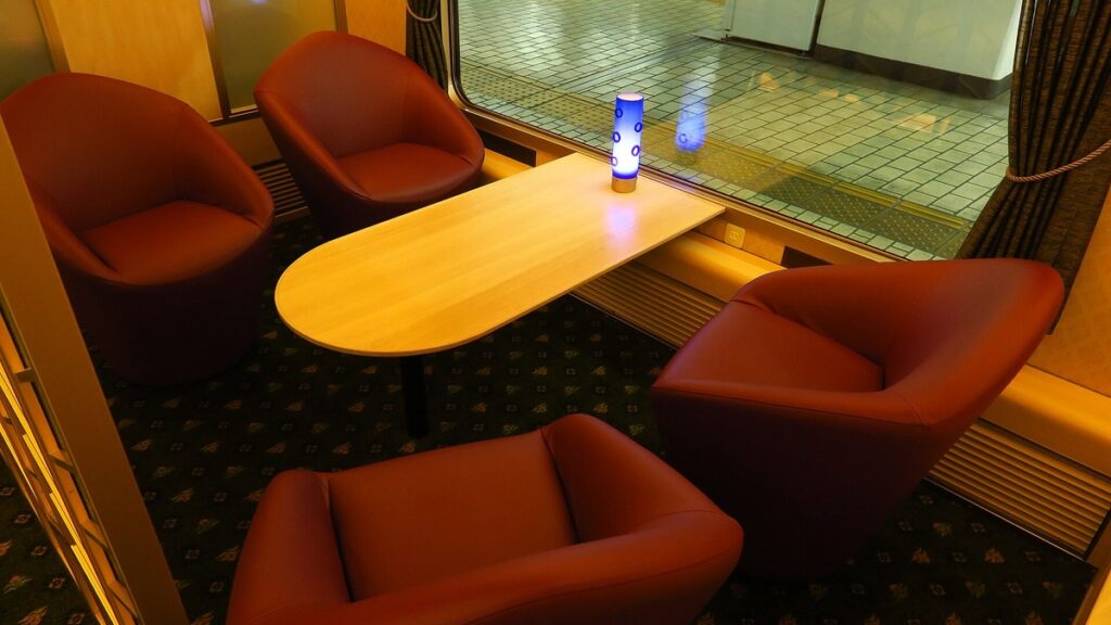 Salon seats with four armchairs around a table inside the Aoniyoshi sightseeing train